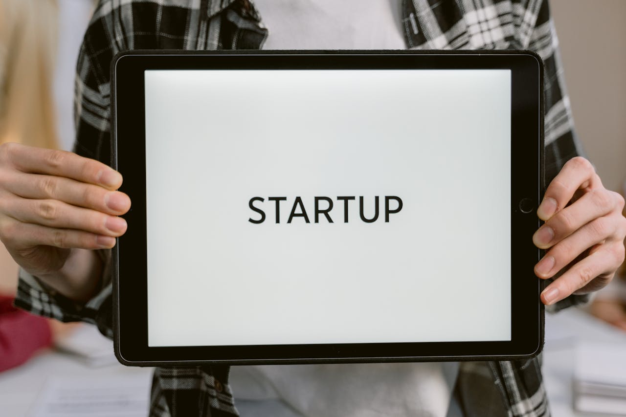 Person holding a digital tablet displaying the word STARTUP, representing new business concepts.